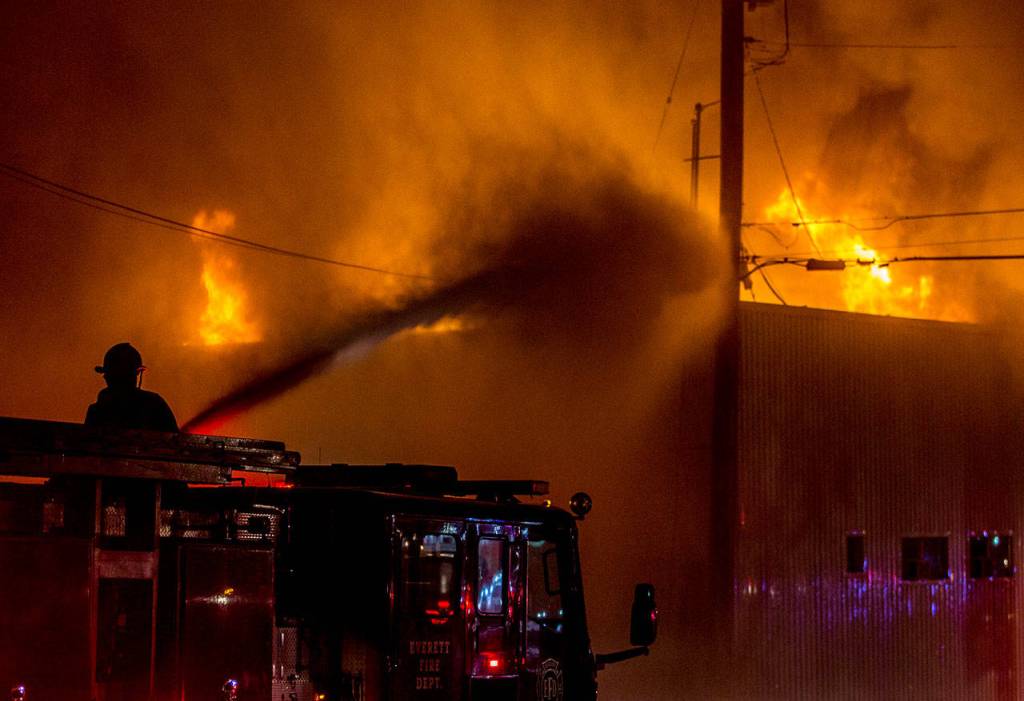 A Everett firefighter sprays water on the Judd & Black appliance store at 3001 Hewitt Ave that burned on Sept. 21, 2018, in Everett. (Olivia Vanni / Herald file)