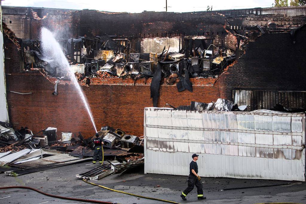 Everett firefighters spray water on the still smoking Judd & Black appliance store on Sept. 22, 2018, in Everett. (Olivia Vanni / Herald file)