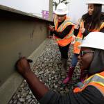 Sequoia High students Sarjo Jallow (lower right), Emanuel Ellis (top left) and Claudia Infante sign their names on the final beam for the roof of the new YMCA building on Colby Avenue on Friday in Everett. (Andy Bronson / The Herald)