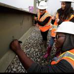 Sequoia High students, Sarjo Jallow, Emanuel Ellis, top, and Claudia Infante sign their names on the final beam for the roof of the new YMCA building on Colby Avenue on Friday, Jan. 25, 2019 in Everett, Wa. (Andy Bronson / The Herald)