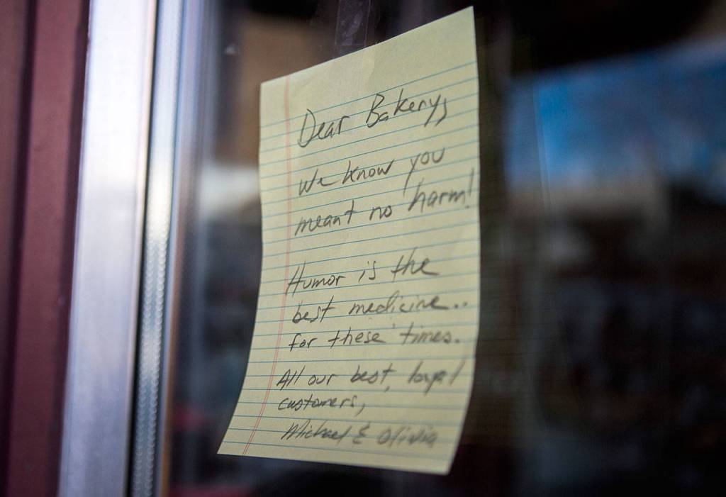 A note from a customer hangs next to the entrance of the Edmonds Bakery expressing support of the contentious cookie. Someone else put up a Stop the Hate sign a few inches away. (Olivia Vanni / The Herald)