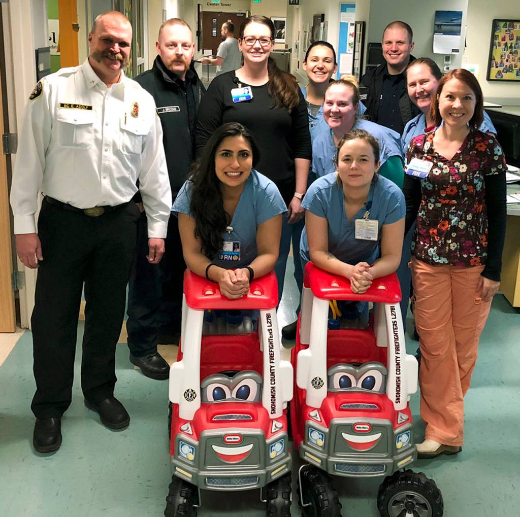 A group of nurses and firefighters pose with the donated fire engines. (Snohomish County Fire District 7)