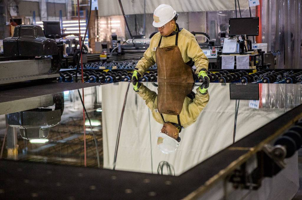 An employee breaks off excess mirror at the Electric Mirror factory in Everett. (Olivia Vanni / The Herald)