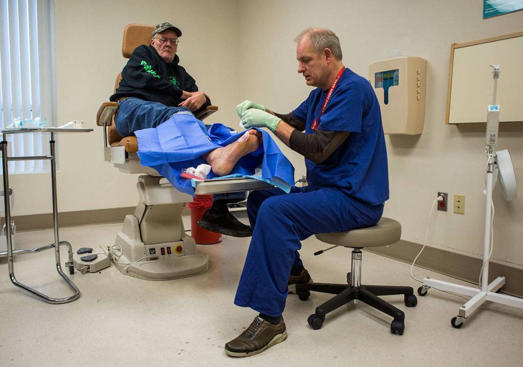 Jonathan Borjeson tends to Steve Matayas foot sore at EvergreenHealths Wound Care and Hyperbarics Center in Monroe. (Olivia Vanni / The Herald)