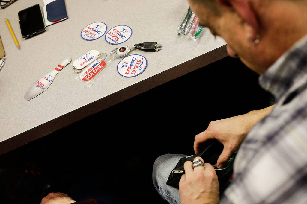 From a pouch, Tony Cea pulls out souvenirs from his highest games and series he has bowled over the years, at Glacier Lanes on Jan. 28 in Everett. (Andy Bronson / The Herald)
