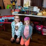 Paityn Cotterill, 10, left, and Isla Cotterill, 9, right, in front of some of their top choice donations Wednesday, Feb. 6 at their home in Snohomish. (Olivia Vanni / The Herald)