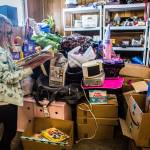 Paityn flips through a pop up book Wednesday, Feb. 6 that was donated next to a large pile of donations being stored in their family garage at their home in Snohomish. (Olivia Vanni / The Herald)