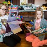 Paityn Cotterill, 10, left, and Isla Cotterill, 9, right, flip through some of their favorite books Wednesday, Feb. 6 at their home in Snohomish. (Olivia Vanni / The Herald)