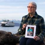 Rosemary Newman poses with a photo of her mother, Hazel Nichols, whose <a href="https://www.heraldnet.com/news/ever-after-get-married-or-buried-on-a-washington-ferry/" target="_blank">ashes she dispersed in the Puget Sound</a> from a ferry at Bracketts Landing Park. (Olivia Vanni / The Herald)