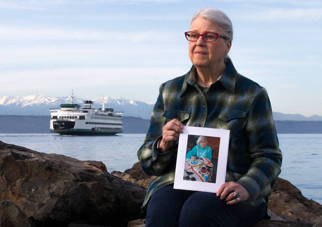 Rosemary Newman poses with a photo of her mother, Hazel Nichols, whose <a href="https://www.heraldnet.com/news/ever-after-get-married-or-buried-on-a-washington-ferry/" target="_blank">ashes she dispersed in the Puget Sound</a> from a ferry at Bracketts Landing Park. (Olivia Vanni / The Herald)