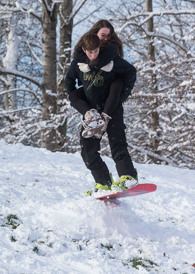With Abbe Balka on his back, Devin Keeler tries to get air off a jump while snowboarding Monday, Feb. 4, at Jennings Park in Marysville. (Andy Bronson / The Herald)
