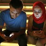 In this 2016 photo, Bahr Abdul Razzak (left) and his wife, Noura Al-Ameer, use their smartphones in Istanbul. The two had been targeted by a mysterious group of undercover operatives, an Associated Press investigation has found. (AP Photo/Petros Karadjias)