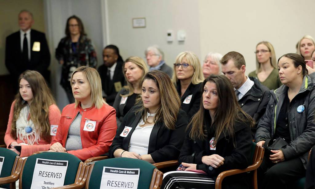 People opposed to a bill that would remove parents ability to claim a philosophical exemption to opt their school-age children out of the combined measles, mumps and rubella vaccine listen to testimony Friday at the Capitol in Olympia. (AP Photo/Ted S. Warren)