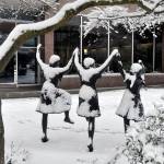 The three girls in the bronze statue Along Colby on Colby Avenue in Everett seemed to be dancing for joy in the snow Saturday morning. (Sue Misao / The Herald)