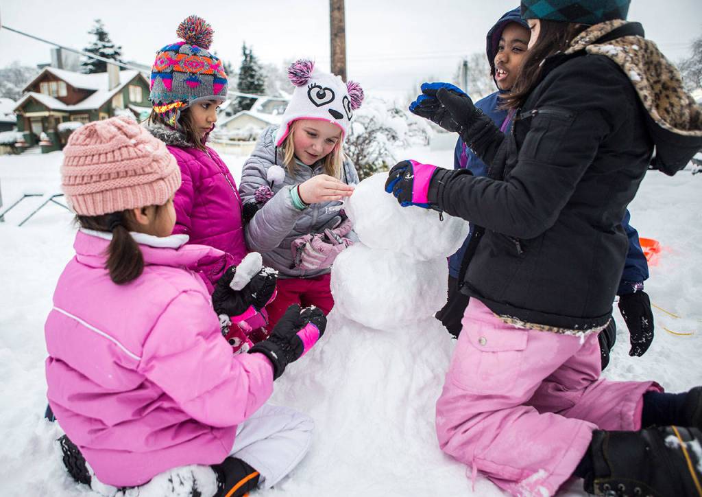 From left: Alexa Urbanozo, 6, Evie Larama, 6, Reese Emerson, 9, Tegan Larama, 9, and Ava Urbanize, 9, make a snowman on Saturday in Everett. (Olivia Vanni / The Herald)