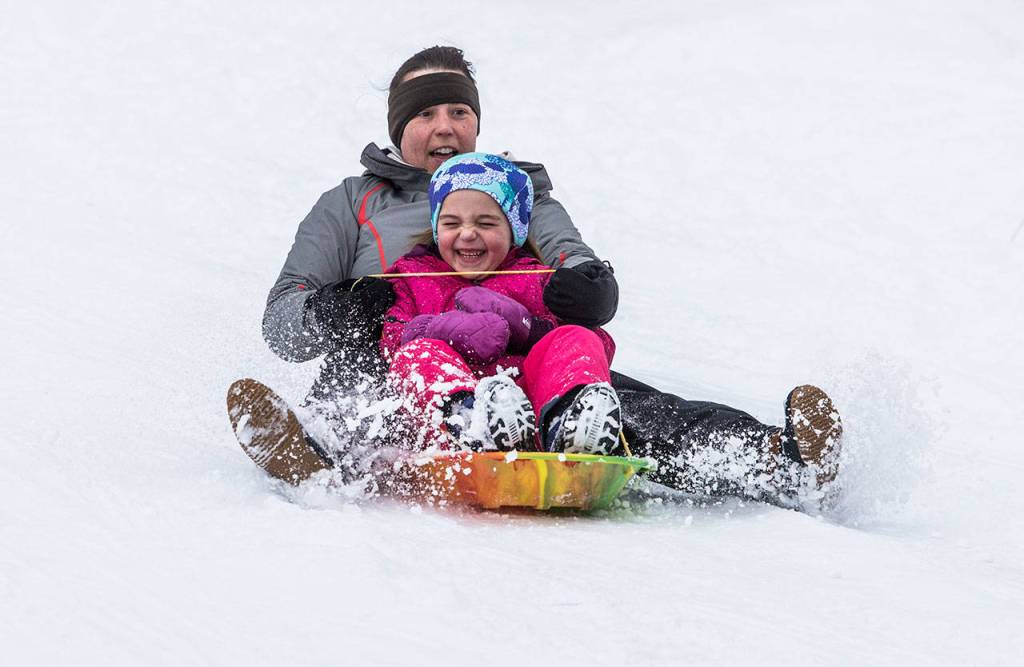 Lacey Harper sleds down a hill with daughter June Harper, 7, on Saturday in Everett. (Olivia Vanni / The Herald)
