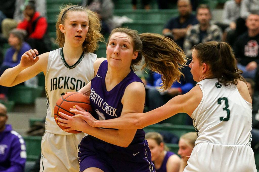 North Creeks Brandi White drives as Jacksons Megan Mattison (left) and Jacksons Mackendra Konig defend during a 4A Wes-King District Tournament play-in game Thursday at Jackson High School in Mill Creek. North Creek beat the Timberwolves 84-70. (Kevin Clark / The Herald)