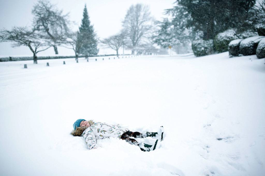 Kinley Stonehocker makes a snow angel in Everetts Bayside neighborhood on Feb. 4. (Julia-Grace Sanders / The Herald)