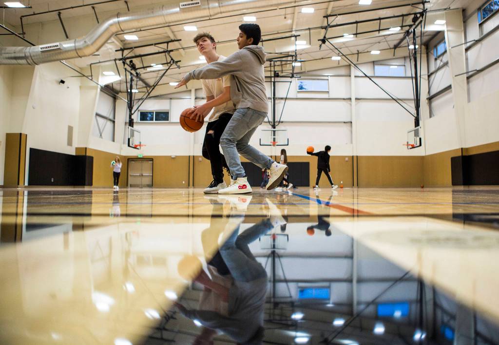 Desmond Curtis, 14, (left) and Ashwin Dahal, 14, (right) play basketball in the new gym at the Mukilteo Boys & Girls Club on Jan. 24 in Mukilteo. (Olivia Vanni / The Herald)