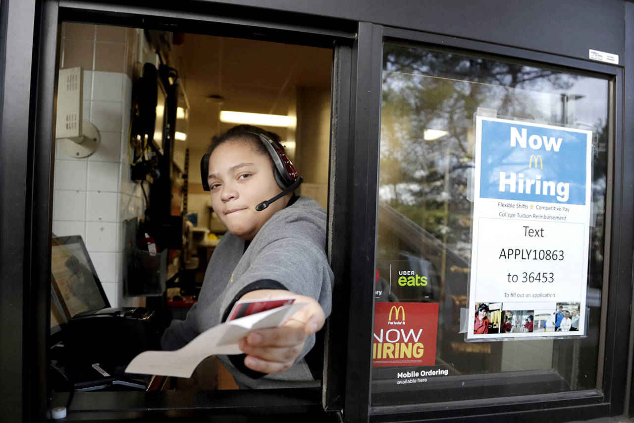 In this Jan. 3 photo, a cashier returns a credit card and a receipt at a McDonald’s window, where signage for job openings are displayed in Atlantic Highlands, New Jersey. On Tuesday, the Labor Department reported job openings jumped 2.4 percent in December to 7.3 million. (AP Photo/Julio Cortez, File)
