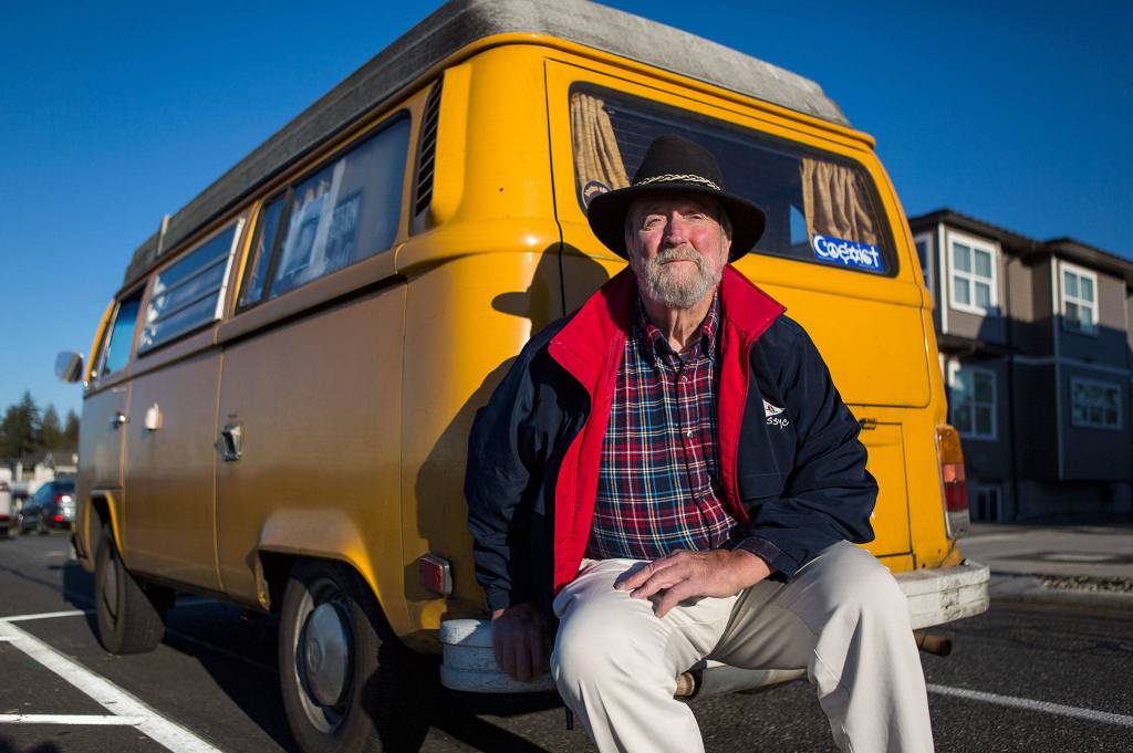 <a href="https://www.heraldnet.com/news/hes-the-man-whose-yellow-vw-van-gets-attention-in-edmonds/" target="_blank">Steven Bell</a> sits on the bumper of his 1976 Volkswagen Westfalia Transporter parked on Sunset Avenue on Jan. 29 in Edmonds. (Olivia Vanni / The Herald)