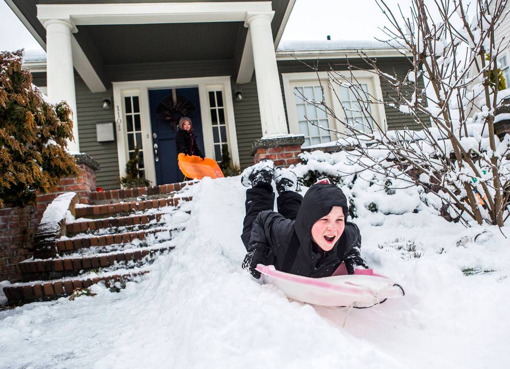 Cobin Chadwick, 11, sleds down a sled hill built off a front porch on Feb. 9 in Everett. (Olivia Vanni / The Herald)