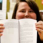 Moniline Winston, 18, opens to a page in the book Listen from the Scriber Lake student writing program. At the top of the page is the name of her story, RISING, and her name. (Dan Bates / The Herald)