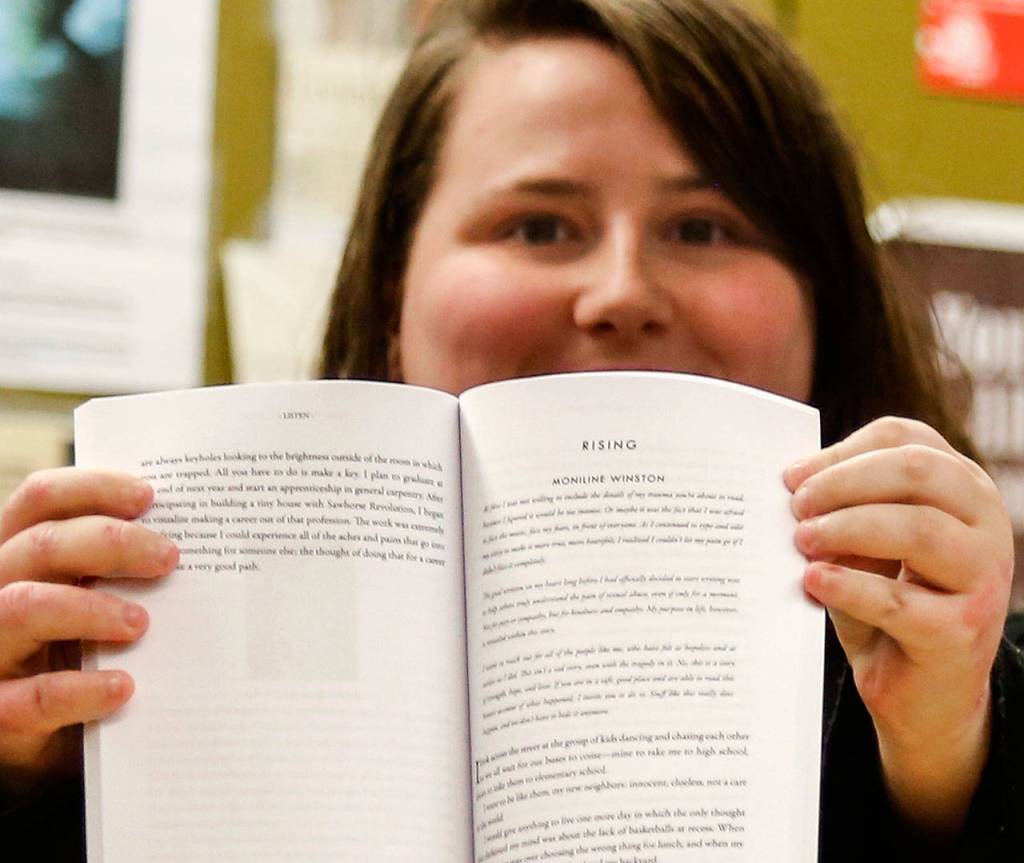 Moniline Winston, 18, opens to a page in the book Listen from the Scriber Lake student writing program. At the top of the page is the name of her story, RISING, and her name. (Dan Bates / The Herald)