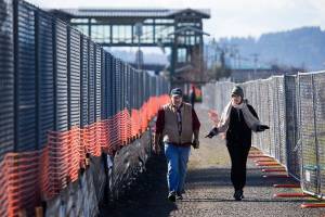 Brad and Linda Guilford chat as they walk along the pedestrian path set up around the new Mukilteo ferry dock construction. The Guilfords live on the hill above the construction and walk daily to observe the progress. (Andy Bronson / The Herald)