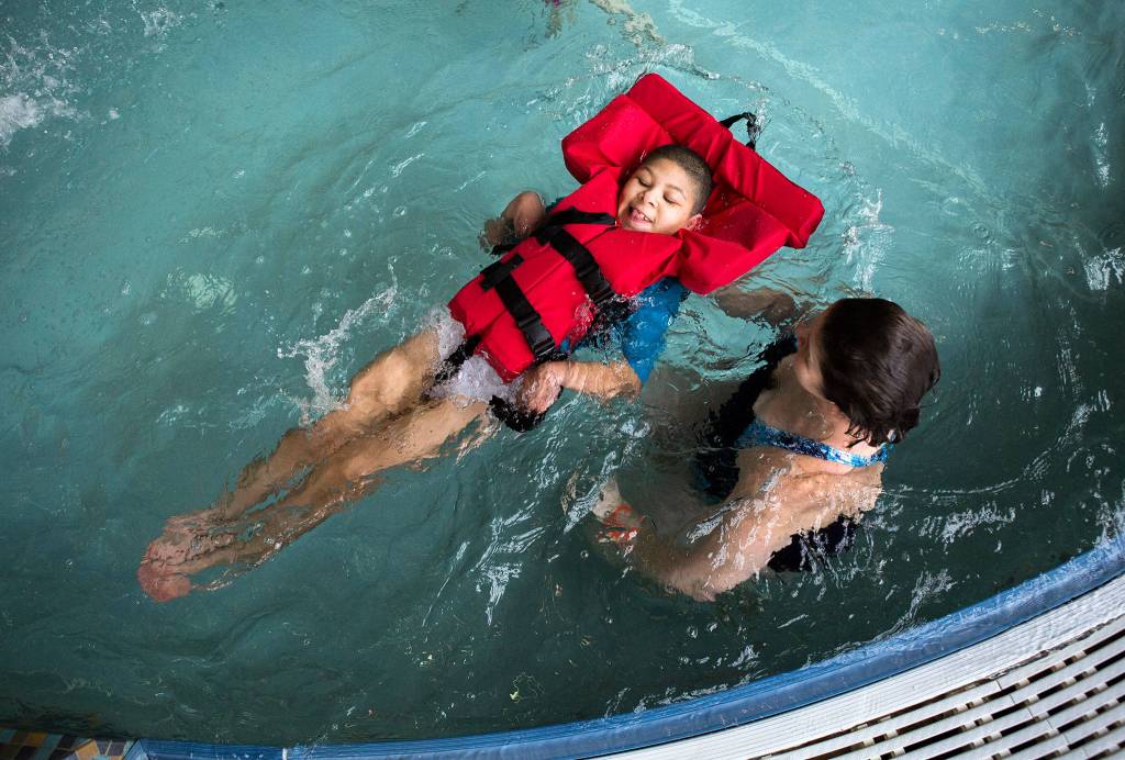 <a href="https://www.heraldnet.com/news/doctors-said-he-might-not-live-past-5-he-just-turned-11/" target="_blank">Jamarious Carpenter</a>, 11, is guided through the water by his mother, Ginger Carpenter, during his birthday celebration at the Lynnwood Recreation Center & Pool on Jan. 20 in Lynnwood. (Olivia Vanni / The Herald)
