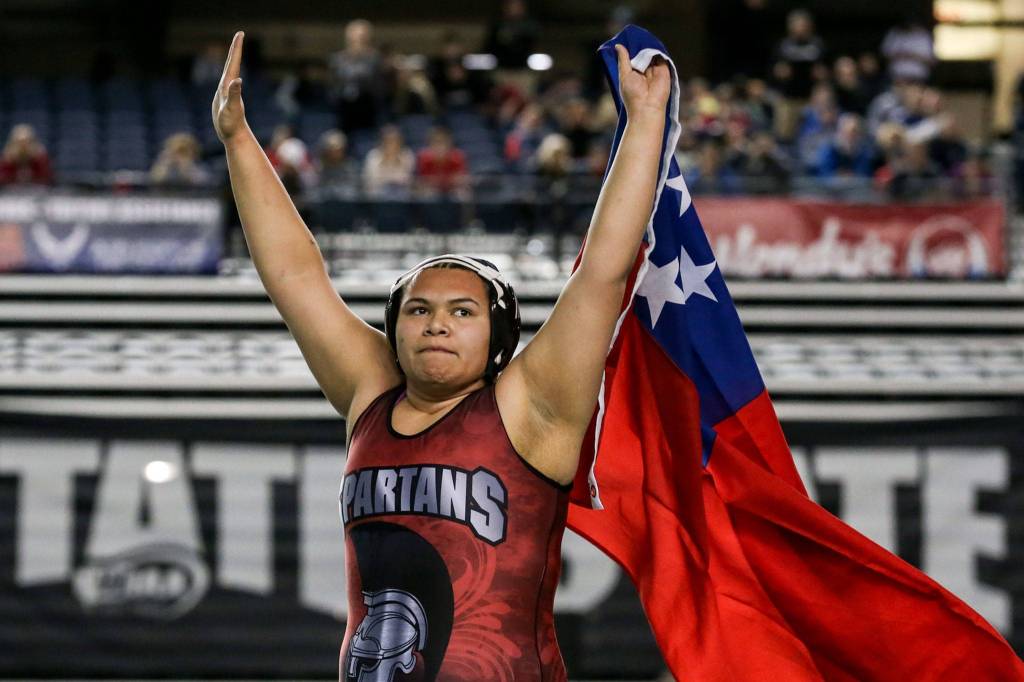 Stanwoods Chanel Siva celebrates with the Samoan flag after her win over Thomas Jeffersons Goddess Ma`alona-Fal in the 235 weight class to win a state title Saturday night during the Mat Classic XXXI at the Tacoma Dome on Feb. 15 in Tacoma. (Kevin Clark / The Herald)