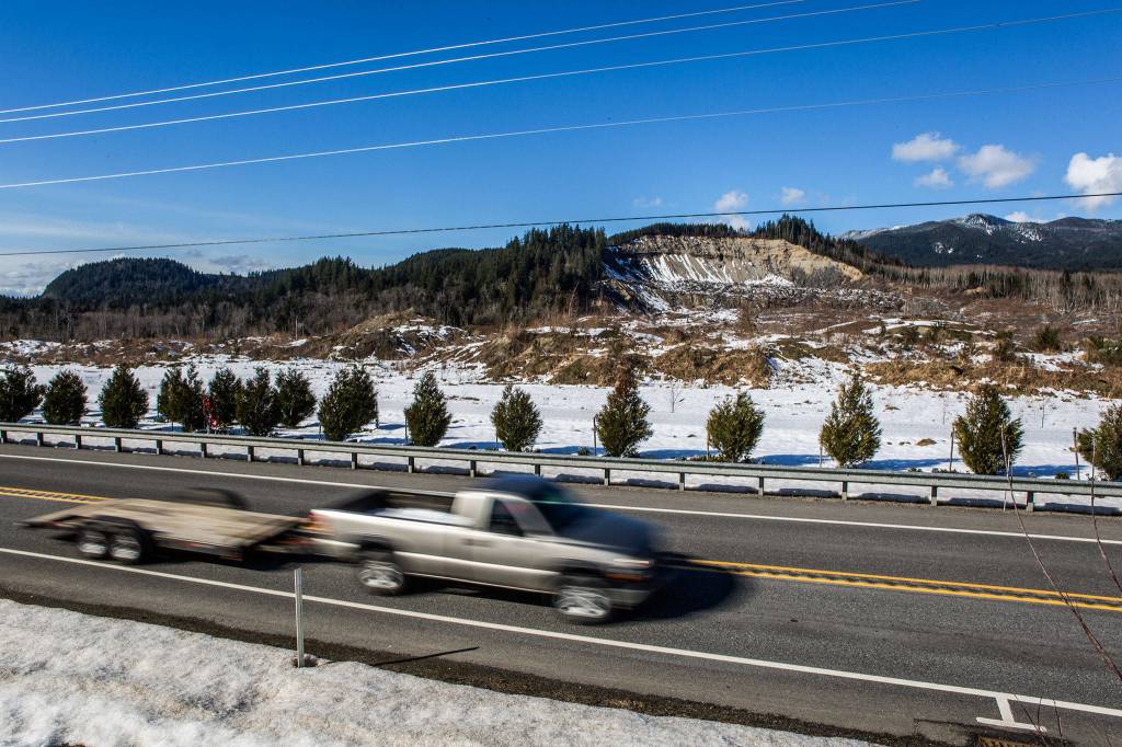 A car pulling an empty trailer drives eastbound along <a href="https://www.heraldnet.com/news/renaming-ensures-drivers-know-what-happened-on-highway-530/" target="_blank">Highway 530 in front of the Oso mudslide</a> site on Feb. 21 in Darrington. (Olivia Vanni / The Herald)