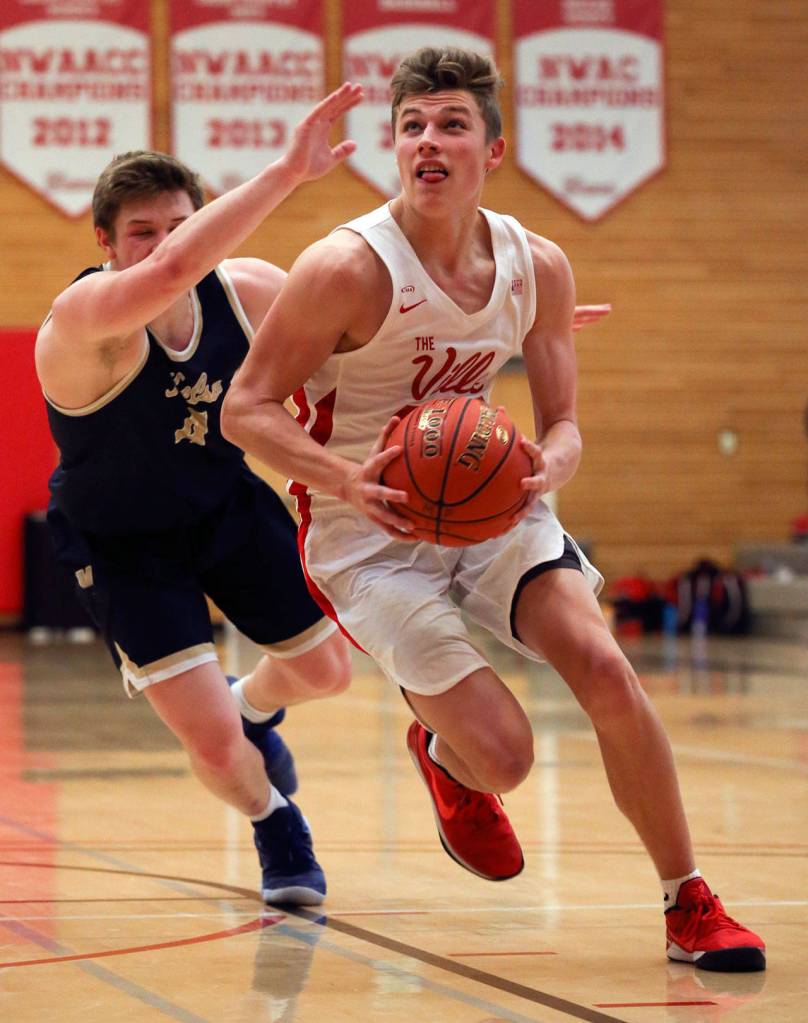 Marysville Pilchucks Aaron Kalab drives to the basket with Kelsos Riley Noah trailing during a 3A state regional game on Feb. 22 at the Walt Price Student Fitness Center on the campus of Everett Community College. (Kevin Clark / The Herald)