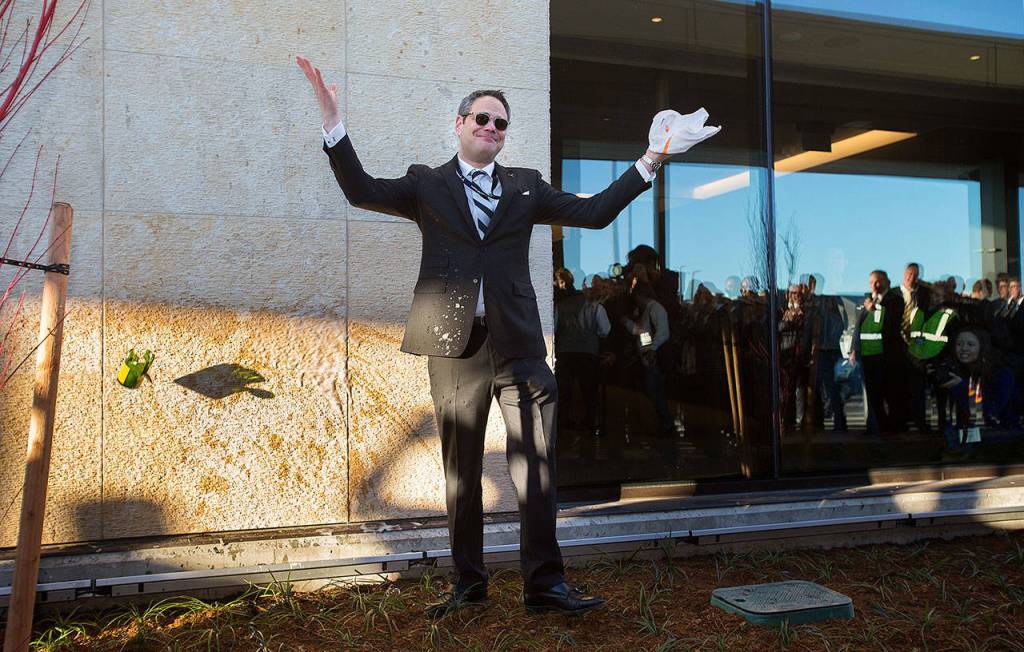 After more than a few tries at breaking a champagne bottle to christen the new passenger terminal at Paine Field, Propeller Airports CEO Brett Smith throws up his hands  and the broken bottle. (Andy Bronson / The Herald)