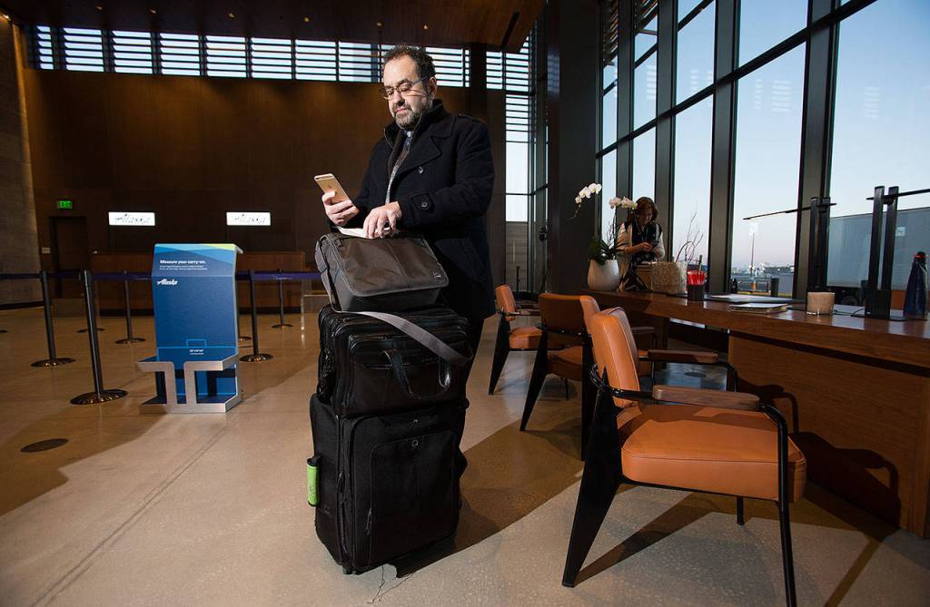 After checking in first, Richard Burns, of Bothell, looks over his boarding pass on the opening day of the Paine Field terminal on Monday. (Andy Bronson / The Herald)