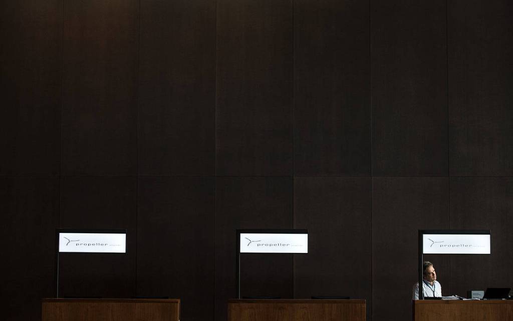 Surrounded by rich dark brown wood walls, a man works on getting the ticket counters ready at the Paine Field terminal on Tuesday. (Andy Bronson / The Herald)