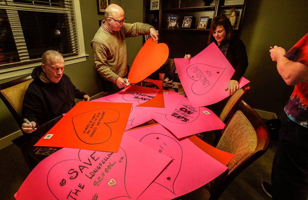 Local preservationists Jack ODonnell, (left) Patrick Hall, Andrea Tucker and Paul Popelka cut out, decorate and write messages on colorful paper hearts Thursday evening in advance of Fridays heart-bombing. (Dan Bates / The Herald)