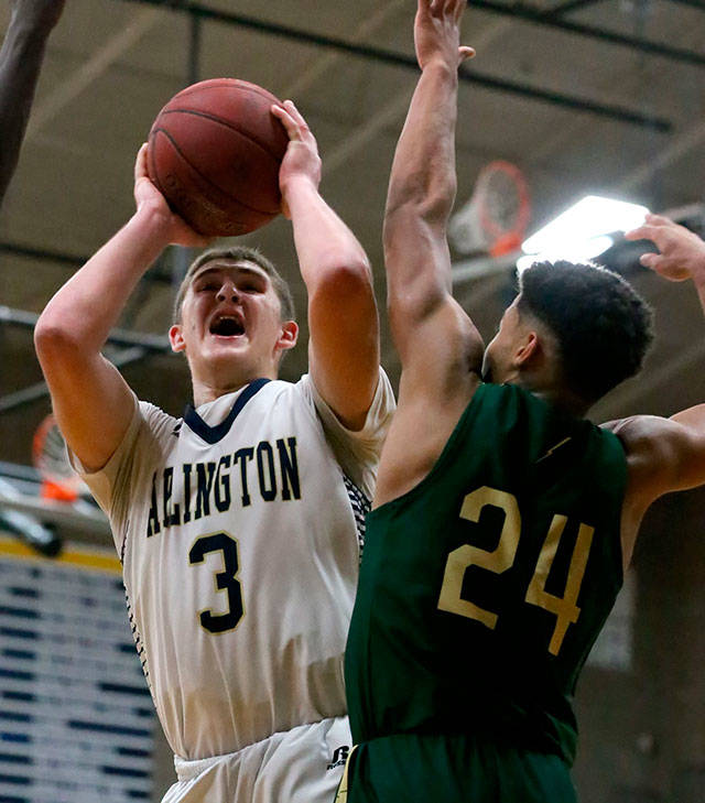 Arlingtons Griffin Gardoski attempts a shot with Marysville Getchells Malakhi Knight defending during a 3A district tournament matchup Feb. 15 at Arlington High School. (Kevin Clark / The Herald)