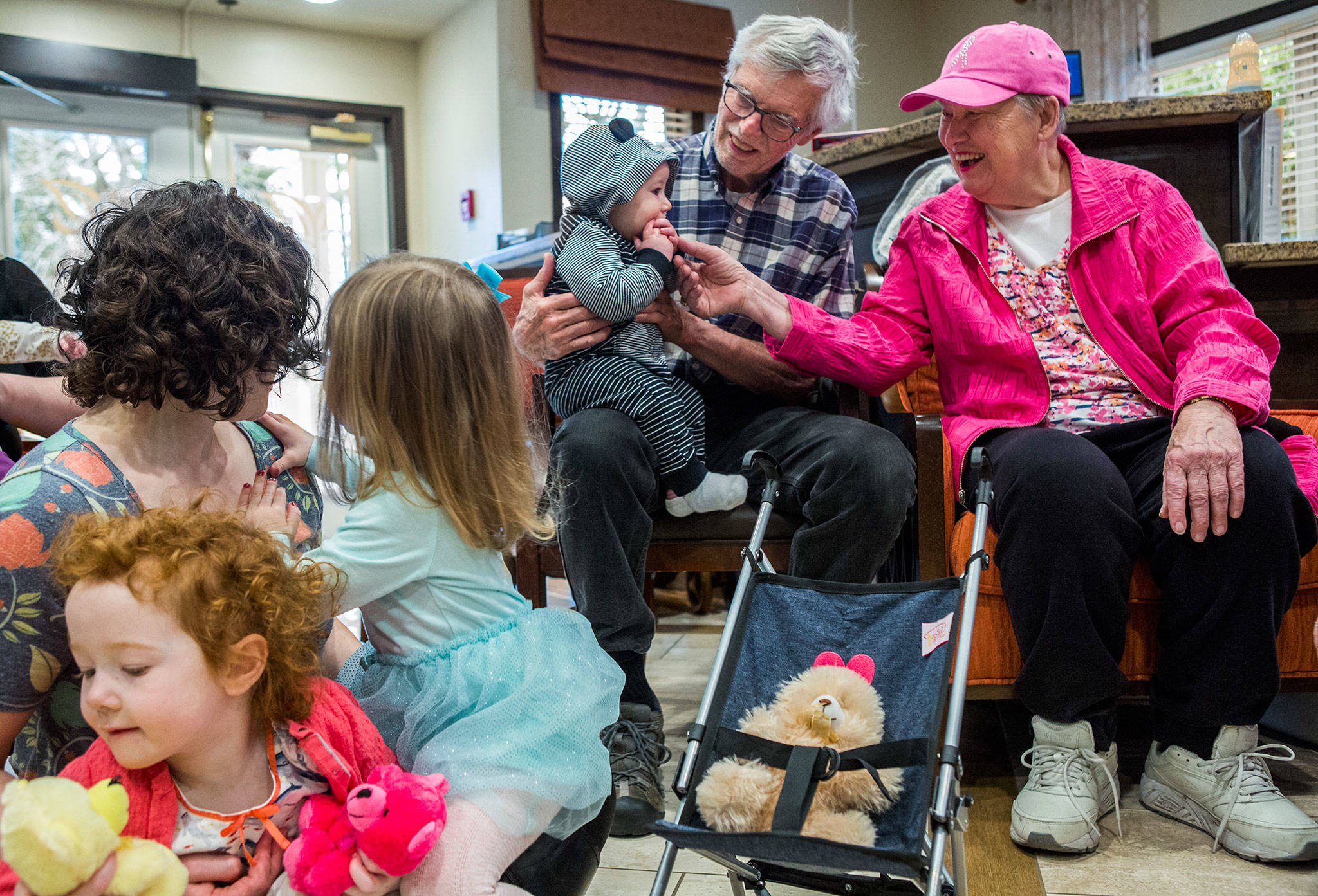 Merrill Coulson, 77, left, holds Oliver Bates, 7 months, while Kathy Kendall, 82, right, plays with his hands during the Seniors & Sprouts program at Pacifica Senior Living in Lynnwood. (Olivia Vanni / The Herald)