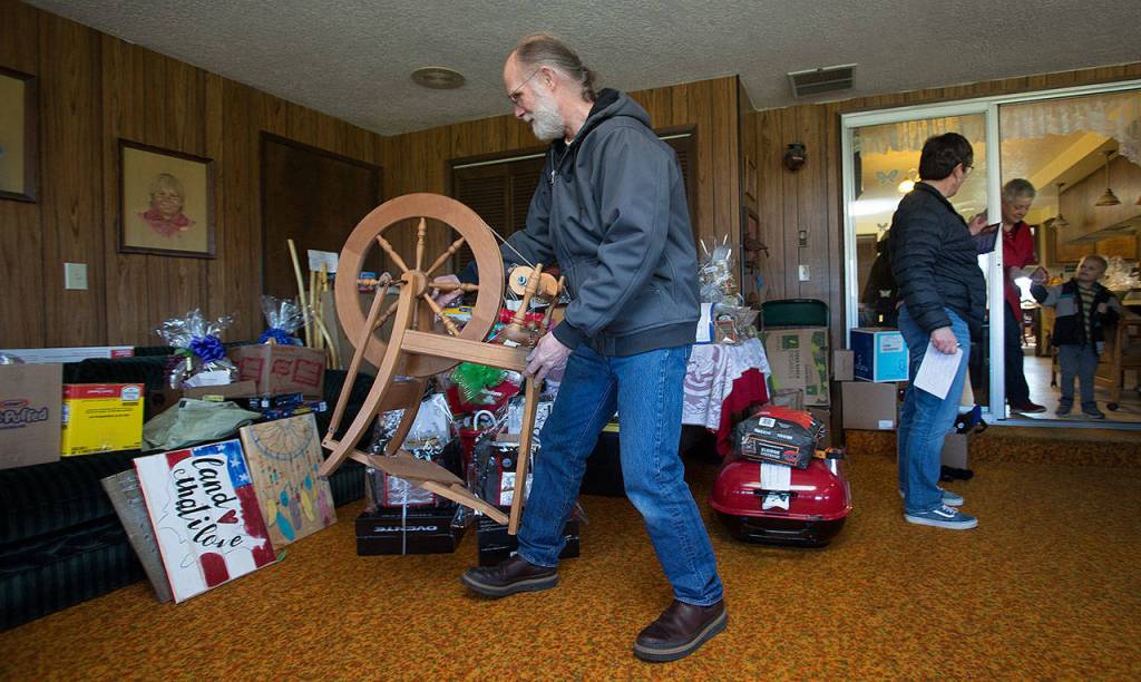 Rick Zahalka places a spinning wheel next to items donated for the Silvana Fair Board Auction. (Andy Bronson / The Herald)