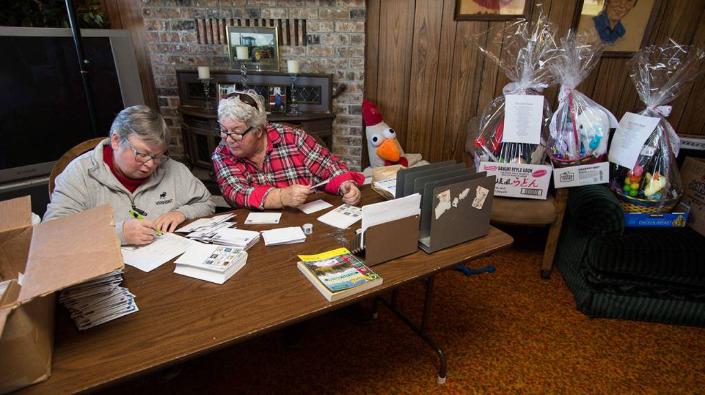 Cathy Pryor (right) looks at her sister Char Taylor as they address and label thank you cards for the Silvana Fair Board Auction. (Andy Bronson / The Herald)