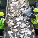A worker pulls out a dress from recycled waste Aug. 28, 2018 at Waste Managements recycling center in Woodinville. (Andy Bronson / The Herald)
