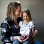 Jessica Beckstrand (left) sits with her daughter Layla, 4, who holds some of the money raised and cards made for their familys non-profit called Strong Cares Guild, at their home on Feb. 26 in Marysville. (Olivia Vanni / The Herald)