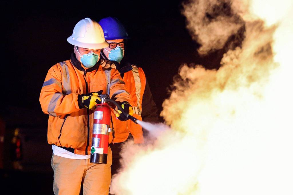 Marcelino Camilo (left) and Hector Ferreyra extinguish the training fire during C.E.R.T. class Thursday night at Everett Fire Department Station 4 on March 14, 2019. (Kevin Clark / The Herald)