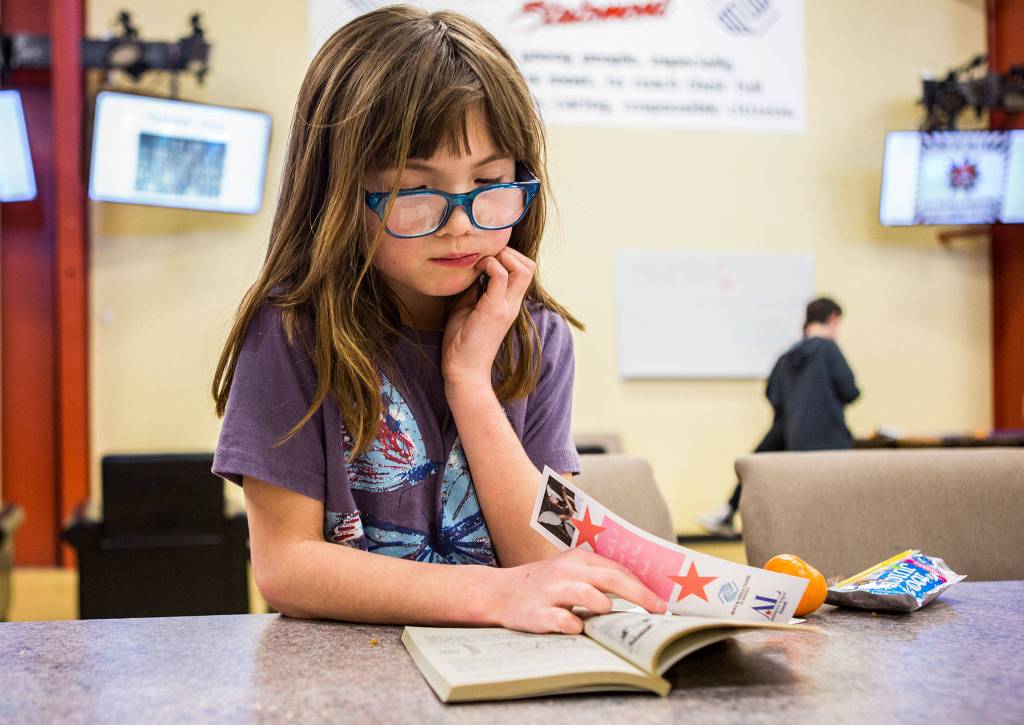 Sierra Ford, 9, reads Blooming Rainforest, a book she picked out during the Assistance League of Everetts book donation event at the Granite Falls Boys & Girls Club on Feb. 28 in Granite Falls. (Olivia Vanni / The Herald)