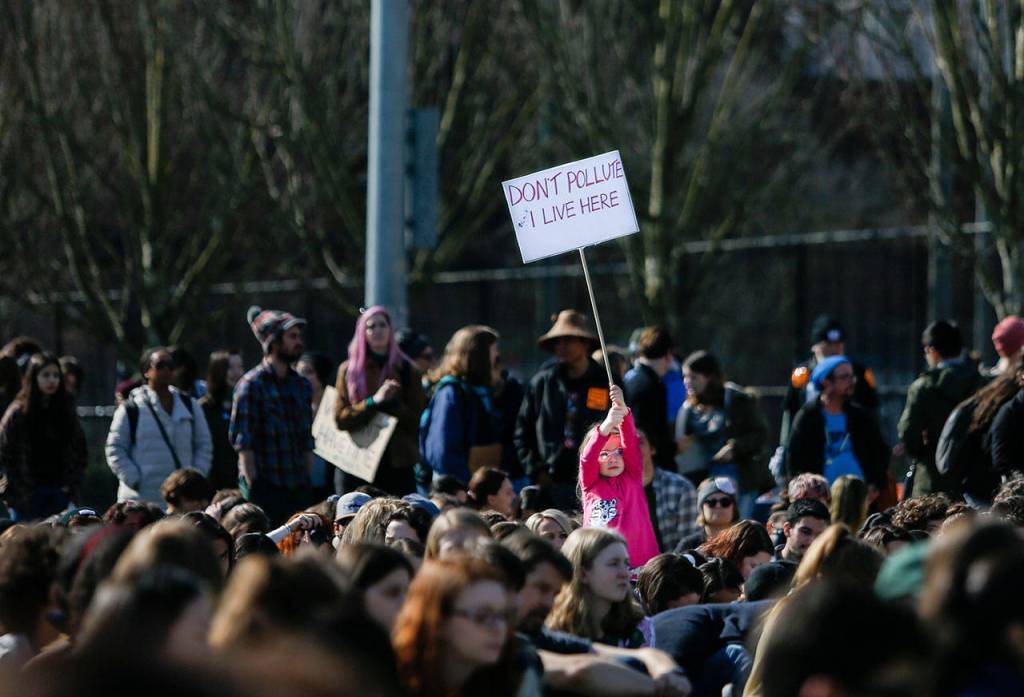 A young girl holds up a Dont Pollute I Live Here sign during the Youth Climate Strike at Cal Anderson Park in Seattle on Friday. (Olivia Vanni / The Herald)