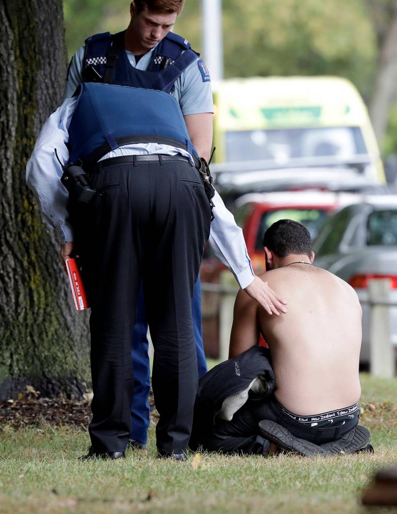 Police console a man outside a mosque in central Christchurch, New Zealand, on Friday. (AP Photo/Mark Baker)