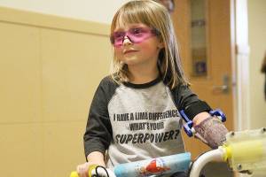 Michaela Reed navigates an obstacle course of stools in the hallway of Oak Harbor High School with her new bike. (Laura Guido / Whidbey News-Times)