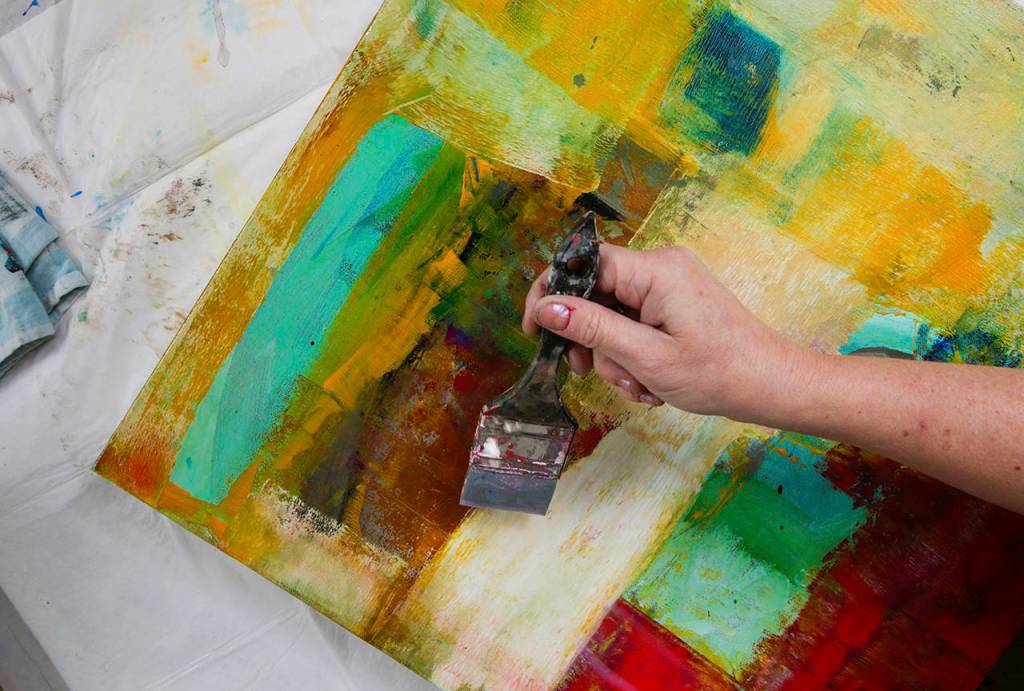 Cort puts a coat of varnish on a painting. (Andy Bronson / The Herald)