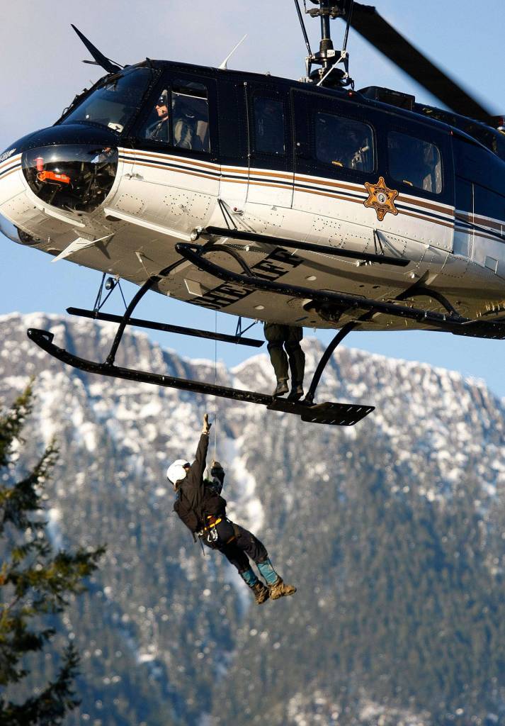 A search and rescue worker is lowered into the trees to retrieve a body found east of the mudslide on March 23, 2014. (Genna Martin / The Herald)